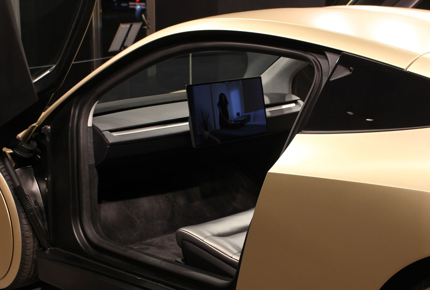Looking into a Cybercab through its raised door: a dark seat, a slim dashboard and a center screen, with no steering wheel or pedals.